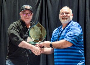 Award recipient Kevin Morris (left) shaking hands and posing with his award with TMSC Chair Maurice Maness (right).